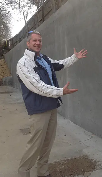 Chad Costello standing in front of finished retaining wall